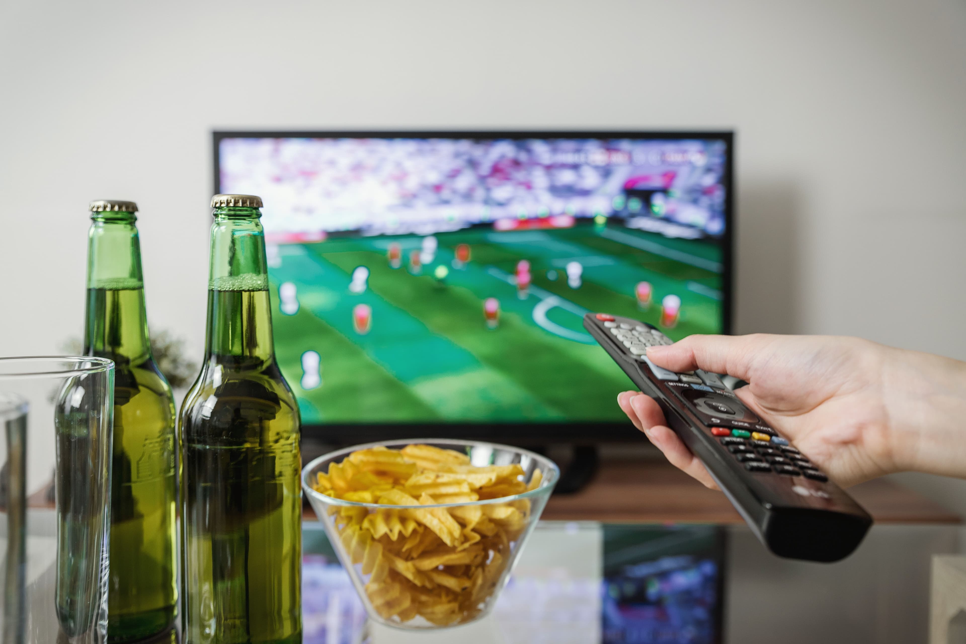 Henkilö rentoutuu kotona suuren television ja suoratoistosisällön äärellä
