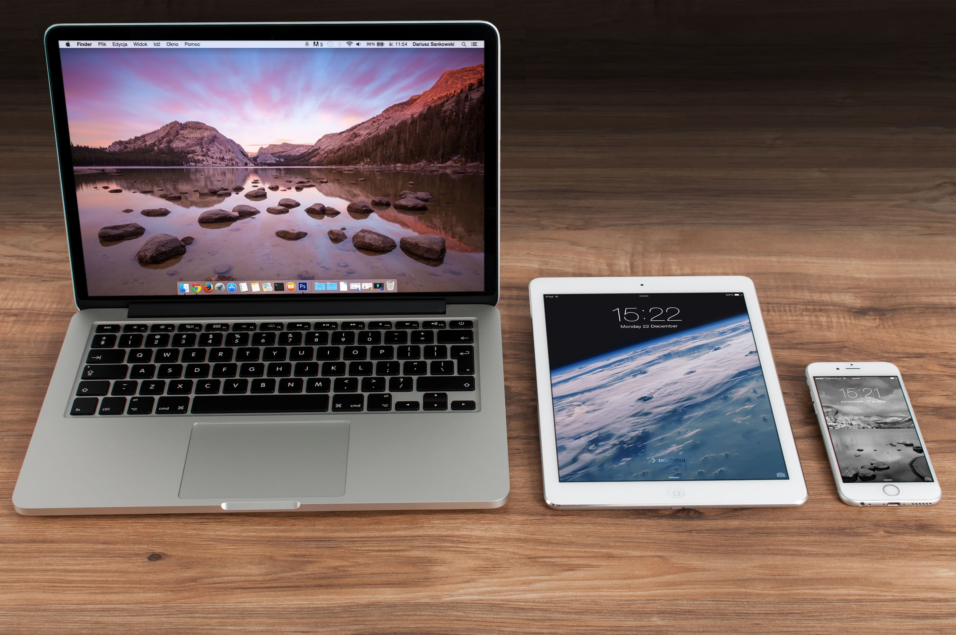 MacBook, iPad ja iPhone vierekkäin puisella työpöydällä